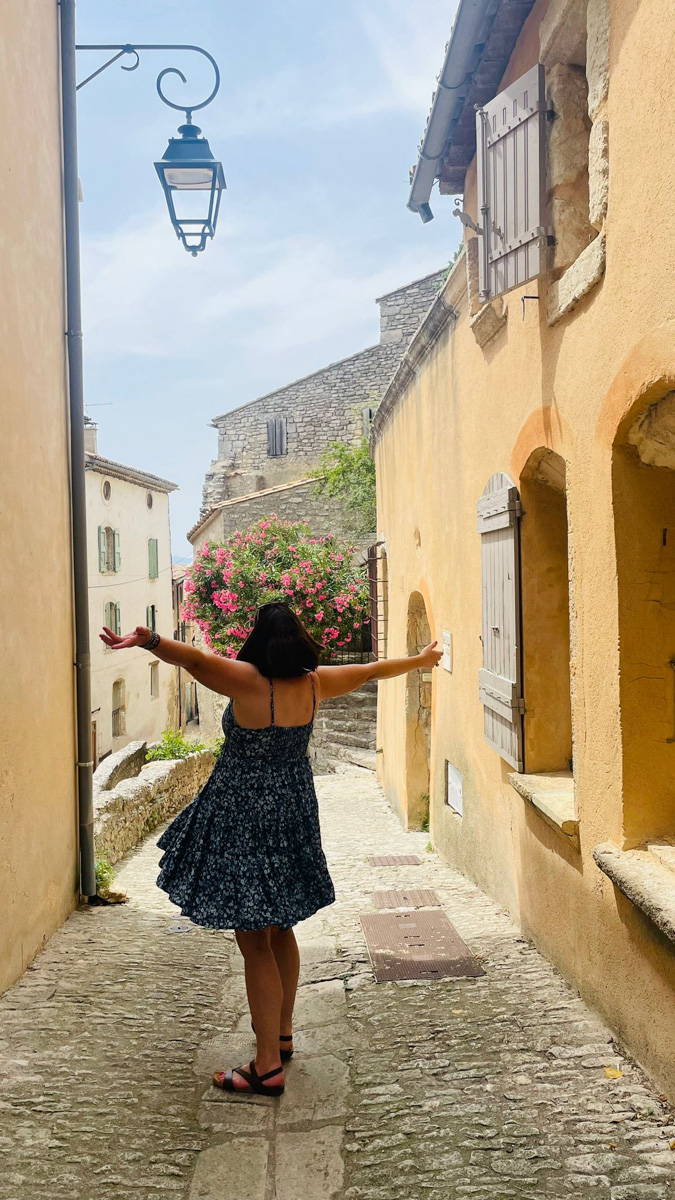 Woman with arms open in a Provençal village alley